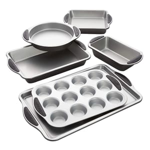 A set of nonstick baking pans includes a muffin pan, two rectangular baking pans, a circular cake pan, and two loaf pans, each with silicone handles for easy grip.