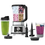 Ninja kitchen system with a blender, interchangeable blades, and attachable cups for smoothies. Includes ingredients like ice, berries, and seeds, showcasing versatility.