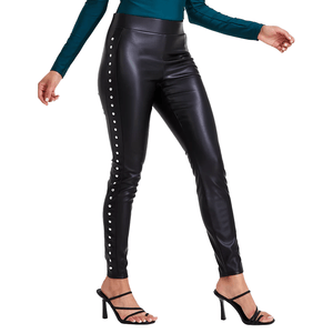 Black faux-leather leggings with side stud detailing, featuring a high-waisted fit. Pairing with strappy black heels and a teal long-sleeve top, they offer a sleek and stylish look.