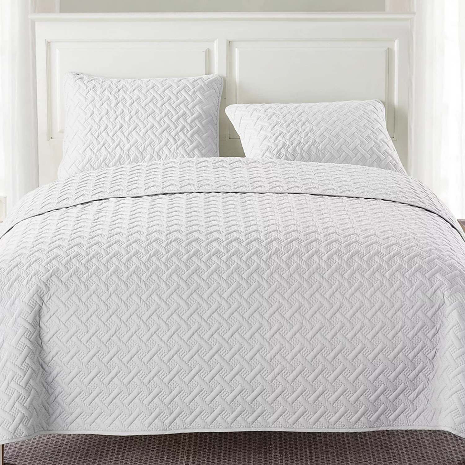 White quilted bedding set with a geometric pattern, featuring two pillows and a matching bedspread.