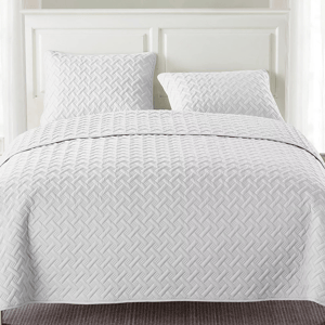 White quilted bedding set with a geometric pattern, featuring two pillows and a matching bedspread.