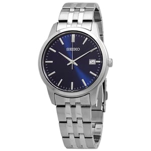 Seiko Men's Essentials Quartz Watch features a sleek blue dial, silver-tone hands and hour markers, a date window at 3 o'clock, and a stainless steel bracelet with a deployment clasp.