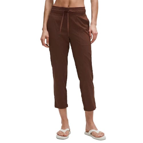 A person is modeling brown cropped pants with a drawstring waist, paired with white sandals.