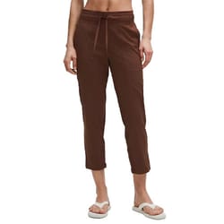 A person is modeling brown cropped pants with a drawstring waist, paired with white sandals.