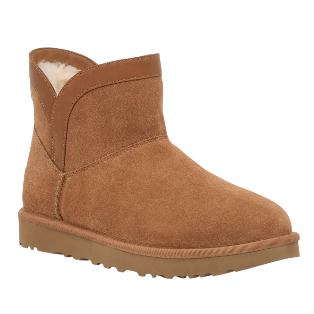 A tan ankle boot with a suede texture, featuring a rounded toe and sheepskin or faux fur lining, resting on a flat rubber sole.