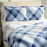 A bed set featuring a blue and white plaid pattern, including two pillowcases and a matching blanket.