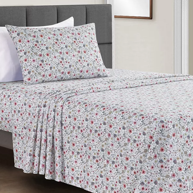 A floral patterned bedsheet set with matching pillowcases on a bed with a grey headboard.