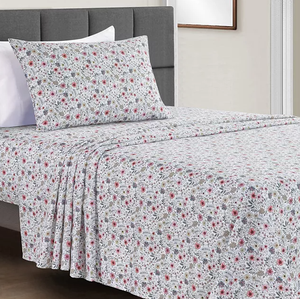 A floral patterned bedsheet set with matching pillowcases on a bed with a grey headboard.