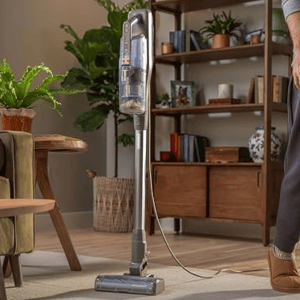Upright vacuum cleaner with a self-standing design shown in a living room setting, emphasizing the convenience of parking and cleaning at your own pace.