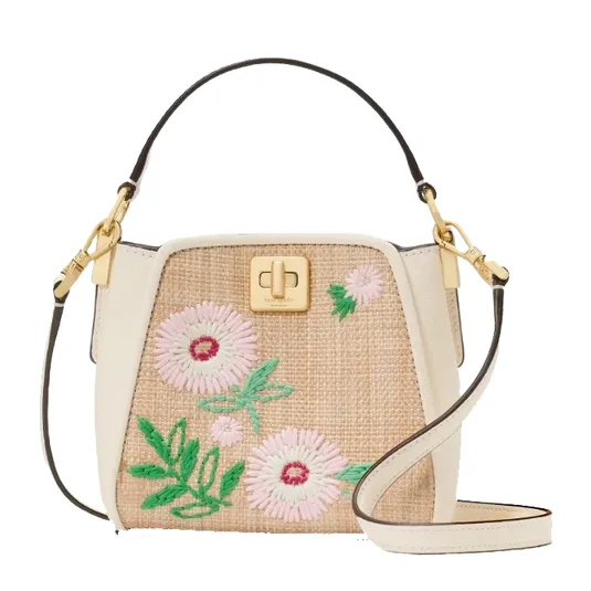 A stylish handbag with floral embroidery on a woven base, featuring a white leather trim, gold-tone hardware, and adjustable shoulder strap.
