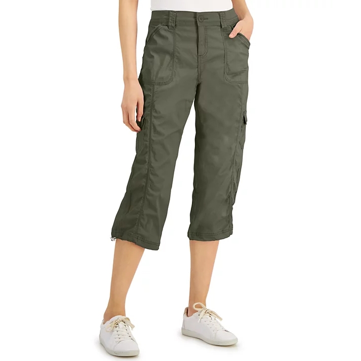 A person is wearing olive-green cargo capri pants with multiple pockets, paired with white sneakers.