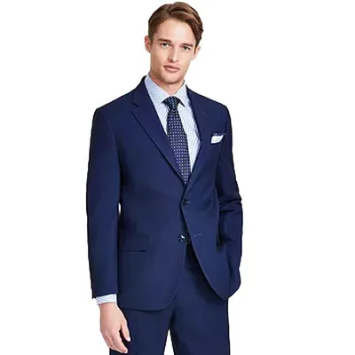 A man is wearing a dark blue suit with a white dress shirt and a blue tie featuring polka dots.
