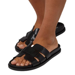 A pair of black slip-on sandals with a sleek design and open toe, featuring multiple straps across the foot.