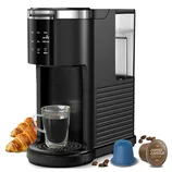 Single-serve coffee maker with a glass cup, croissants, coffee beans, and coffee capsules.