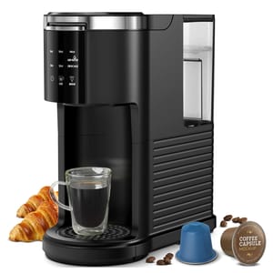 Single-serve coffee maker with a glass cup, croissants, coffee beans, and coffee capsules.