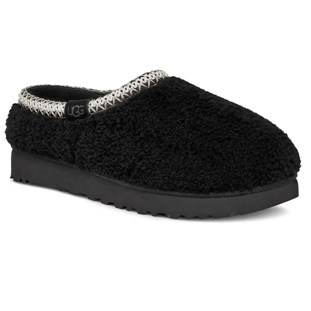 Black UGG Tasman Maxi Curly Slippers feature a plush curly fabric with a woven trim around the opening and a UGG tag, resting on a sturdy black sole.