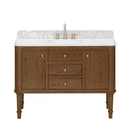 A wooden bathroom vanity with two side cabinets and three center drawers, featuring a white marble countertop and gold faucet hardware.