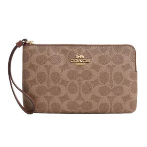 A Coach wristlet featuring the brand's signature \“C\“ pattern, crafted in a brown leather-like material, with a gold-tone logo and a detachable wrist strap.