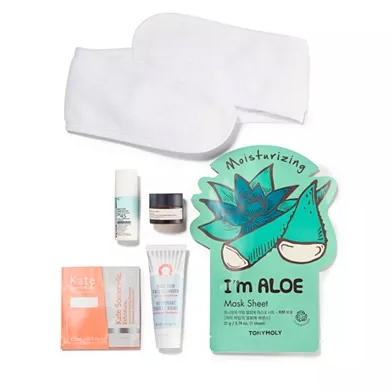 A collection of skincare items includes moisturizing aloe mask sheet, facial serum, under-eye cream, sunscreen, skin-perfecting gel, exfoliating wipes, and a pair of white spa gloves.