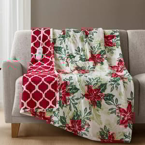 A floral-patterned, heated blanket with a red and white motif and attached control panel draped over a light gray sofa.