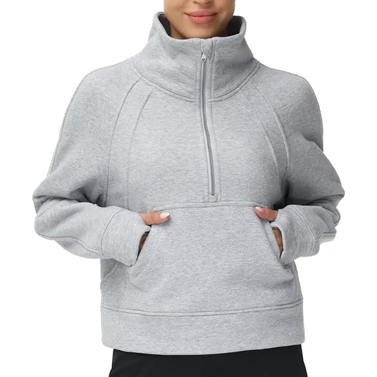 A person wears a gray, long-sleeve, half-zip pullover sweatshirt with a high collar and a kangaroo pocket.