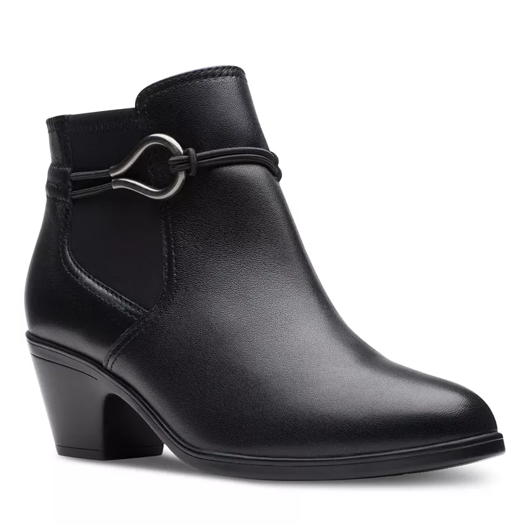 The Clarks Emily 2 Kaylie Dress Booties are sleek black ankle boots with a mid-height block heel and decorative strap detail featuring a silver metal loop. The boots have a smooth leather finish, offering a stylish and versatile look.