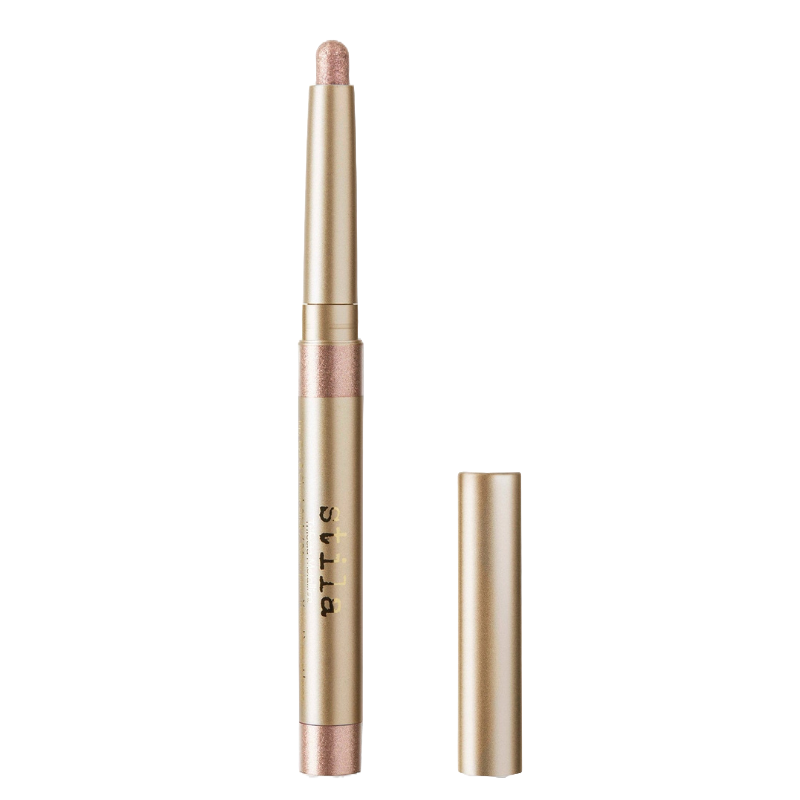 Stila Trifecta Metallica Stick is a gold-colored, cylindrical cosmetic stick with a shimmery pink tip and a detachable cap, used for makeup application.
