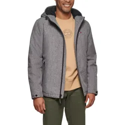 A man is wearing a gray hooded jacket over a beige sweatshirt with a logo, paired with olive green pants. The jacket has a small logo on the chest and features a zippered front and side pockets.