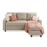 Beige L-shaped sofa with three cushion backs, adorned with a cream and a checkered brown pillow. A pink knit throw blanket is draped over the chaise section.