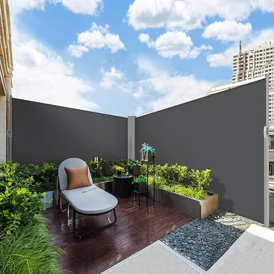 Retractable side awning, 236\“ x 63\“, provides privacy and wind protection on a patio. Features a sleek, modern design with a dark-colored fabric, complemented by a wooden deck and surrounding greenery.