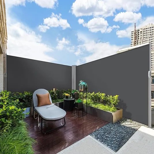 Retractable side awning, 236\“ x 63\“, provides privacy and wind protection on a patio. Features a sleek, modern design with a dark-colored fabric, complemented by a wooden deck and surrounding greenery.