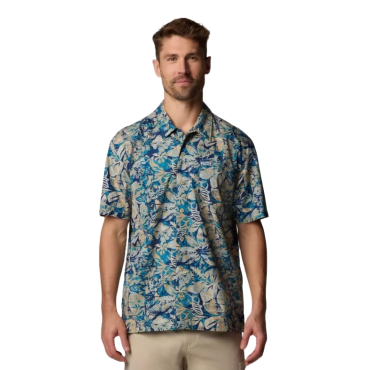 A man is wearing a short-sleeve, blue and beige floral-patterned button-up shirt paired with light-colored pants.