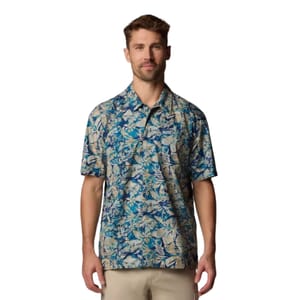 A man is wearing a short-sleeve, blue and beige floral-patterned button-up shirt paired with light-colored pants.