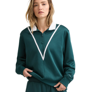 A woman wearing a green pullover with a white V-shaped stripe and a zipper at the collar. The outfit includes matching green pants.