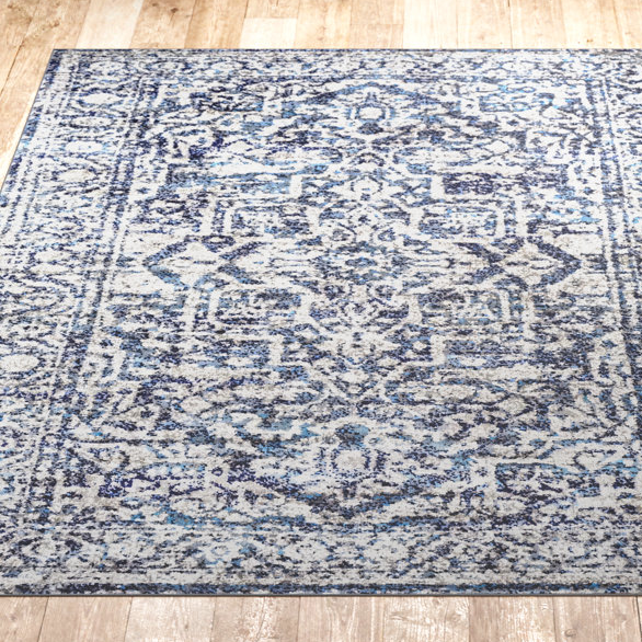 An 8' x 10' area rug featuring an intricate pattern with shades of blue and white, set against a hardwood floor.
