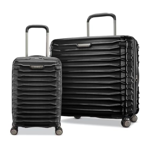 Two black hard-shell suitcases of different sizes with four wheels each, featuring a textured, layered design and telescopic handles.