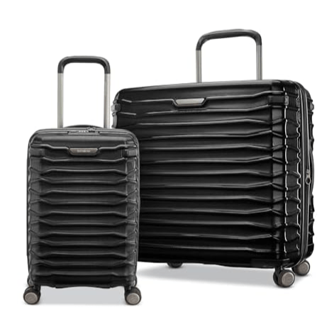 Two black hard-shell suitcases of different sizes with four wheels each, featuring a textured, layered design and telescopic handles.