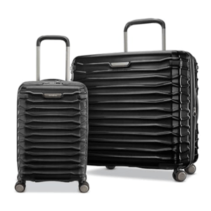Two black hard-shell suitcases of different sizes with four wheels each, featuring a textured, layered design and telescopic handles.