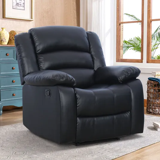 A black leather recliner with a padded design featuring wide armrests, a high back, and a side lever for reclining. It is placed on a rug near a window, with a blue chest in the background.