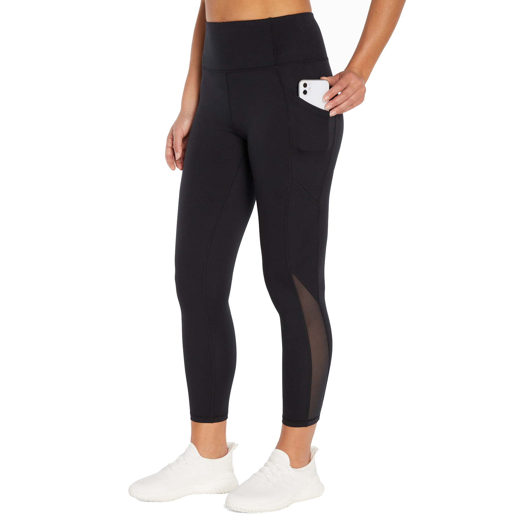 Black leggings with a high waistband, side pocket holding a phone, mesh panel details on the lower leg, paired with white athletic shoes.