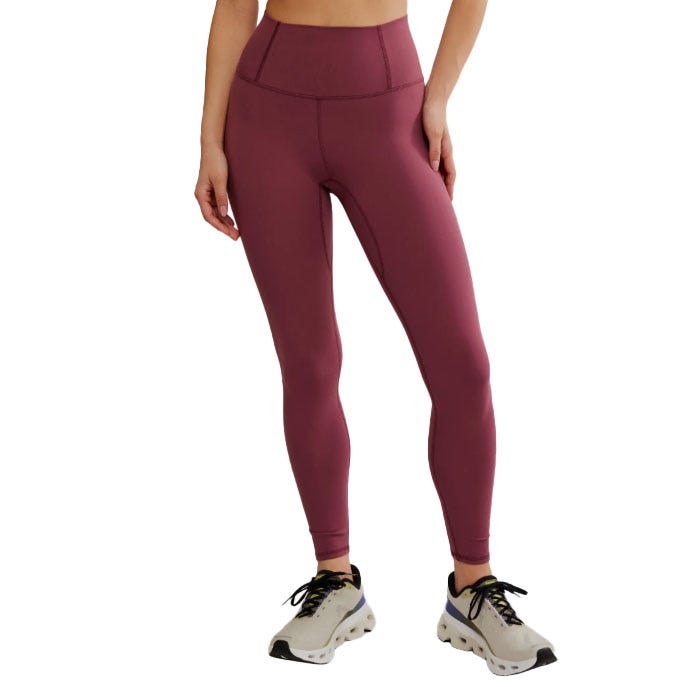 A person is wearing high-waisted burgundy leggings paired with light-colored sneakers.