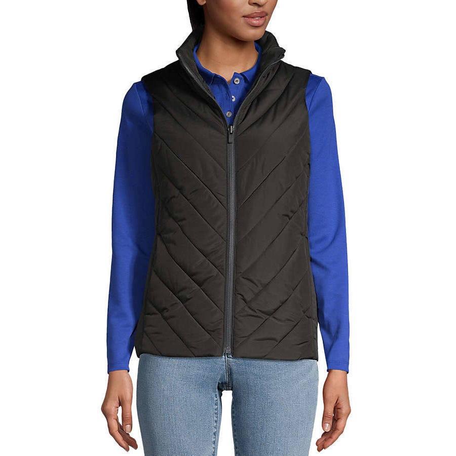 A person is wearing a black quilted vest over a blue long-sleeve shirt paired with light blue jeans.
