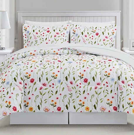 A floral-patterned comforter set featuring colorful flowers on a white background, including a comforter and two matching pillow shams, displayed on a bed.