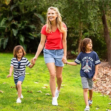 A woman and two children walking outdoors, wearing casual clothing.