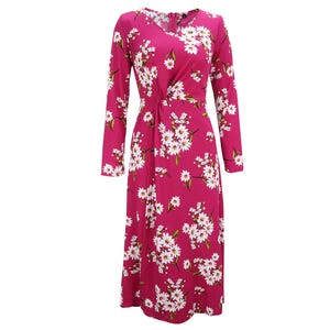 A long-sleeve, dark pink dress featuring a white floral pattern with green leaves, designed with a fitted waist and a flowy silhouette.
