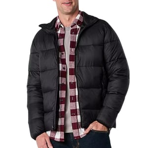 A black men's puffer jacket with a quilted design, featuring a front zipper and side pockets. The jacket is worn over a burgundy and white plaid shirt and white t-shirt, paired with dark jeans.