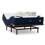 A bed setup featuring a mattress with a navy-blue border, adjustable base, and a set of white linens and pillows, all labeled as DreamCloud.