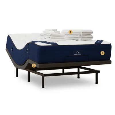 A bed setup featuring a mattress with a navy-blue border, adjustable base, and a set of white linens and pillows, all labeled as DreamCloud.