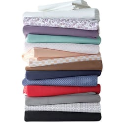 A stack of folded bed sheets in various colors and patterns, featuring shades of white, floral, purple, mint, peach, beige, brown, blue, red, gray, and black.