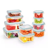 A set of transparent, airtight plastic food storage containers in various shapes, filled with items like almonds, carrots, strawberries, oranges, grapes, peppers, watermelon, and salad greens.